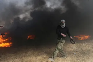 New Gallery: Demonstrator passes by burning tires during clashes with Israeli troops at a protest