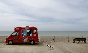 A dog passes by an ice-cream van by an empty beach at Brighton A dog passes by an ice-cream van by an empty beach at Brighton