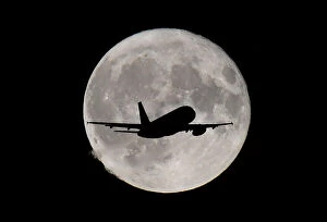 Images Dated 22nd September 2019: FILE PHOTO: A passenger plane passes in front of the full moon as it makes its final