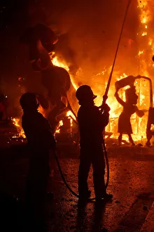 firemen spray water at figures of a monument as it burns during the finale of the Fallas firemen spray water at figures of a monument as it burns during the finale of the Fallas