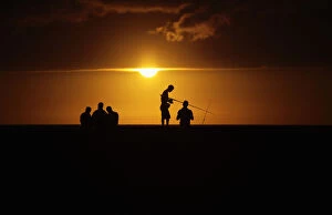Images Dated 28th April 2012: Fishermen stand on Havanas seafront boulevard El Malecon as the sun sets