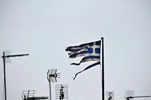Greece Gallery: A frayed Greek national flag flutters among antennas atop a building in central Athens