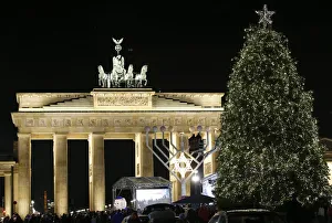 A giant menorah stands next to a Christmas tree in front of the Brandenburg gate to A giant menorah stands next to a Christmas tree in front of the Brandenburg gate to