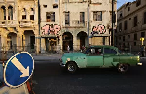 Images Dated 19th March 2012: Two graffiti artists paint on a building on Havanas seafront boulevard El Malecon