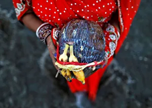 A Hindu devotee holds offerings as she worships the rising sun while standing in the A Hindu devotee holds offerings as she worships the rising sun while standing in the