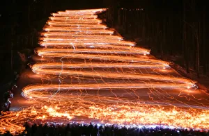 Hundreds of skiers and snowboarders descend from a slope while holding lit torches Hundreds of skiers and snowboarders descend from a slope while holding lit torches