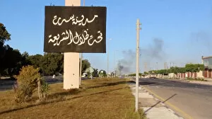 Still image of an Arabic sign with smoke rising in background as forces aligned with