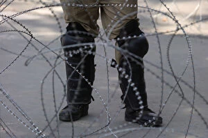 Images Dated 12th August 2019: An Indian police officer stands behind the concertina wire during restrictions