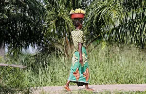 An internally displaced Congolese woman carries a basin containing bananas as she walks An internally displaced Congolese woman carries a basin containing bananas as she walks