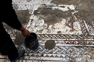 An Israel Antiquities Authority worker holds a bucket while cleaning a mosaic floor An Israel Antiquities Authority worker holds a bucket while cleaning a mosaic floor