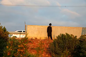 An Israeli ultra-Orthodox Jew looks over a wall as demonstrators block a road during a An Israeli ultra-Orthodox Jew looks over a wall as demonstrators block a road during a