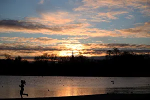 A jogger runs past the Round Pond in Kensington Gardens during sunrise in London A jogger runs past the Round Pond in Kensington Gardens during sunrise in London