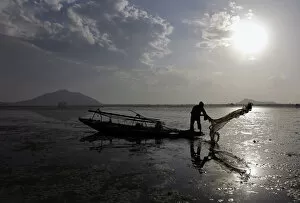 Images Dated 28th September 2010: A Kashmiri fisherman throws a net into the waters of the Dal Lake in Srinagar