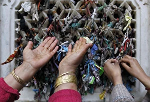 Images Dated 5th March 2012: A Kashmiri Muslim woman prays as another one ties a thread on the window of the shrine of