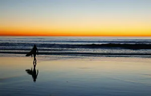 A lone surfer heads home after surfing past sunset in Leucadia A lone surfer heads home after surfing past sunset in Leucadia