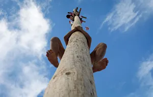 A man climbs up a wooden pole to get a prize during celebration of Maslenitsa A man climbs up a wooden pole to get a prize during celebration of Maslenitsa