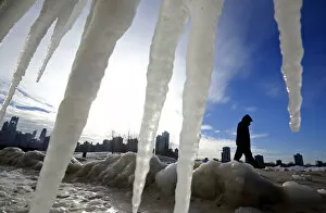 Images Dated 7th January 2014: Man is framed by icicles as he walks along a beach in Chicago
