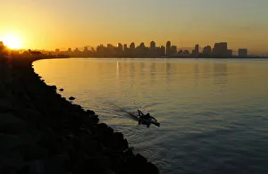 A man glides across the water on a paddle board as the sun rises in San Diego A man glides across the water on a paddle board as the sun rises in San Diego