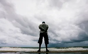 A man looks at the rough sea as rainy clouds gather above during the monsoon period in A man looks at the rough sea as rainy clouds gather above during the monsoon period in