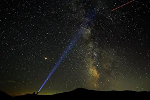 A man points his light at the Milky Way during the peak of the Perseid meteor shower in A man points his light at the Milky Way during the peak of the Perseid meteor shower in