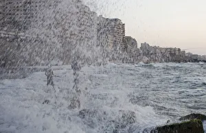 A man is seen though a spray of water from crashing waves as he fishes with his son in a A man is seen though a spray of water from crashing waves as he fishes with his son in a