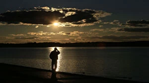 Images Dated 28th October 2012: A man is silhouetted against the reflection of the sun in lake Tegel on a sunny autumn