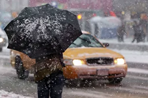 Man stands under a snow-covered umbrella at Times Square in New York Man stands under a snow-covered umbrella at Times Square in New York
