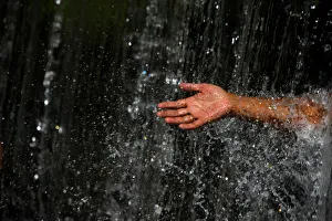 A man takes out his hand throughout the waterfall at Muhan Pokhari in Bhaktapur A man takes out his hand throughout the waterfall at Muhan Pokhari in Bhaktapur
