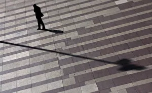 Man talks on mobile phone as he walks on a patterned floor at a yard outside an office Man talks on mobile phone as he walks on a patterned floor at a yard outside an office