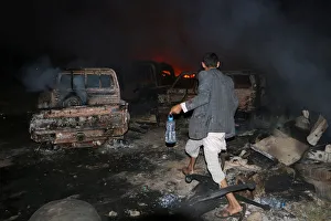 A man walks in front of a fire that broke out at the site of a Saudi-led air strike which A man walks in front of a fire that broke out at the site of a Saudi-led air strike which