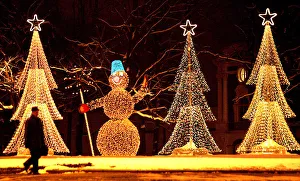 A man walks in past illuminated installations in the shape of a snowman and Christmas A man walks in past illuminated installations in the shape of a snowman and Christmas