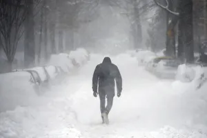 A man walks along a street covered by snow during a winter storm in Washington A man walks along a street covered by snow during a winter storm in Washington