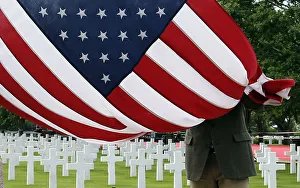 A member of the American War cemetery folds an American flag in Colleville-sur-Me A member of the American War cemetery folds an American flag in Colleville-sur-Me