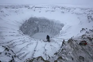 Images Dated 21st November 2014: A member of an expedition group stands on the edge of a newly formed crater on the Yamal Peninsula