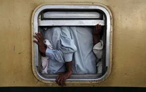 Men are seen at the window of a train as they make their way home, ahead of the Eid Men are seen at the window of a train as they make their way home, ahead of the Eid
