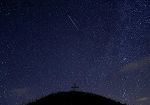 A meteor streaks past stars in the night sky above Leeberg hill during the Perseid meteor A meteor streaks past stars in the night sky above Leeberg hill during the Perseid meteor