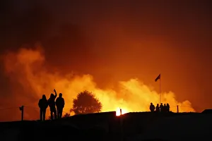 Migrants are seen in silhouette near flames from a burning makeshift shelter on the Migrants are seen in silhouette near flames from a burning makeshift shelter on the