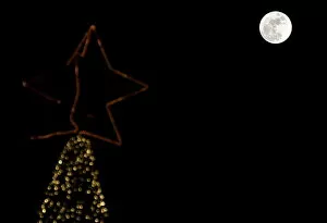 Images Dated 25th December 2015: A full moon rises in the sky over a Christmas tree in Beirut, Lebanon