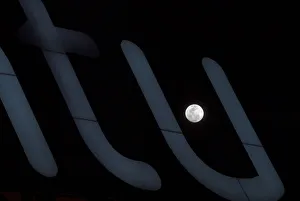 A full moon super moon is seen through a luminous sign in Siero A full moon super moon is seen through a luminous sign in Siero