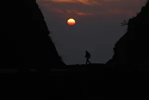A Nepalese man is silhouetted by the setting sun as he walks along the hills at Kailali A Nepalese man is silhouetted by the setting sun as he walks along the hills at Kailali