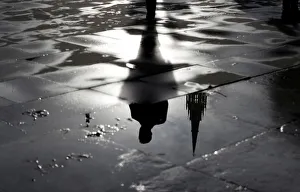 The Palace of Westminster and a man walking are reflected in a puddle in London The Palace of Westminster and a man walking are reflected in a puddle in London