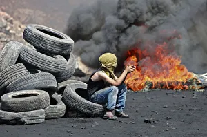 A Palestinian boy sits next to burning tyres during cashes with Israeli soldiers A Palestinian boy sits next to burning tyres during cashes with Israeli soldiers
