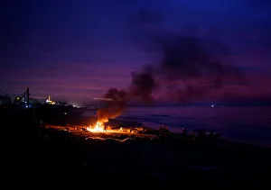 Palestinian fishermen warm themselves by a fire at a beach on a winter day Palestinian fishermen warm themselves by a fire at a beach on a winter day