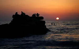 Palestinians ride a boat in the Mediterranean Sea as others enjoy the beach during Palestinians ride a boat in the Mediterranean Sea as others enjoy the beach during