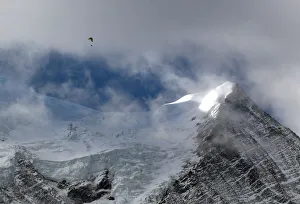 A paraglider flies above the Bossons glacier in the Mont-Blanc massif on a sunny autumn A paraglider flies above the Bossons glacier in the Mont-Blanc massif on a sunny autumn