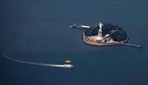 A passenger ferry leaves the The Statue of Liberty and Liberty Island seen from this A passenger ferry leaves the The Statue of Liberty and Liberty Island seen from this
