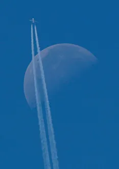 A passenger plane flies in the sky as the Moon is seen in Berlin A passenger plane flies in the sky as the Moon is seen in Berlin