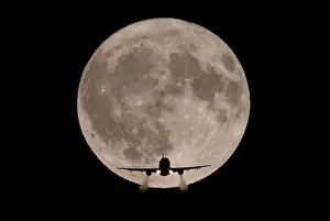 A passenger plane, with a full Harvest moon seen behind, makes its final landing approach A passenger plane, with a full Harvest moon seen behind, makes its final landing approach