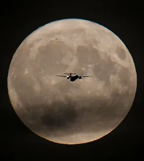 A passenger plane is seen with the full moon behind as it begins its final landing A passenger plane is seen with the full moon behind as it begins its final landing