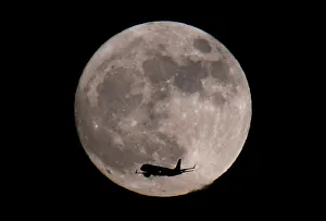A passenger plane, with a supermoon full moon seen behind A passenger plane, with a supermoon full moon seen behind